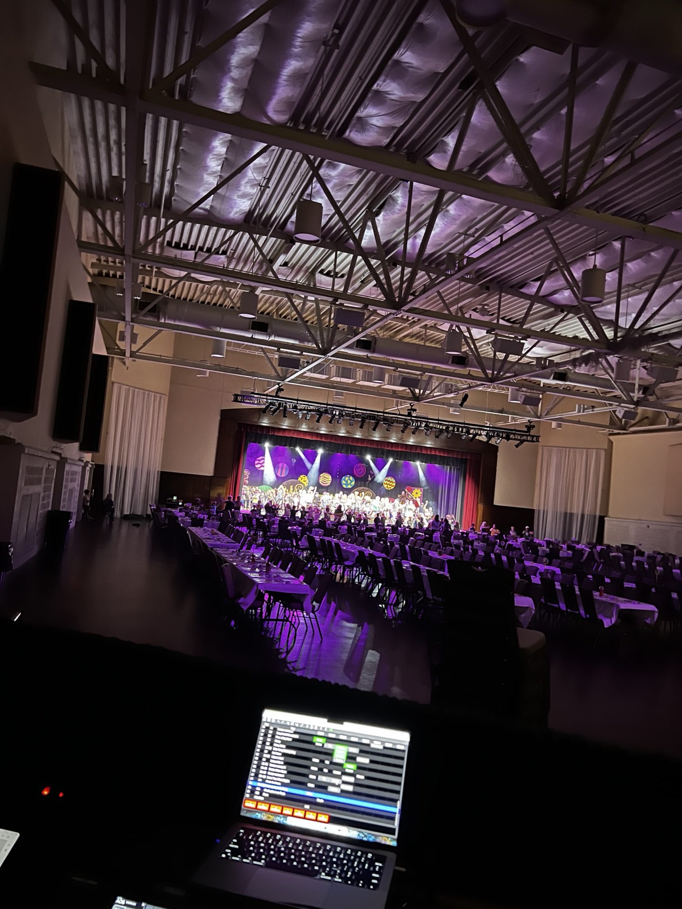Ballroom event with banquet seating facing a stage lit in purple