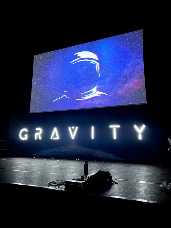 Projection screen showing the Gravity logo in a darkened venue